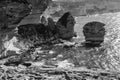 Black and white panoramic view of thr rocky sea shore with clear transparent blue water, cliffs, huge rocks, grass. Bonifacio,