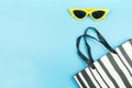 Black and white paper shopping bag and yellow sunglasses on blue background with copy space Royalty Free Stock Photo