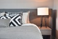 Black and white pattern pillows with gray blanket and white table lamp