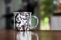 Black and white patterned old metal mug or enamel cup on a wooden table Royalty Free Stock Photo