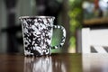Black and white patterned old metal mug or enamel cup on a wooden table Royalty Free Stock Photo