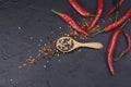 Black and white pepper in a wooden spoon With bright red peppers placed on a dark black table - top view Royalty Free Stock Photo