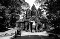 A black and white photo of the Angkor Thom city gate with a smiling face