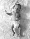 Black and white photo of baby in diapers lying on bed Royalty Free Stock Photo