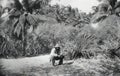 Black and white photo of a bearded man squatting on the background of the jungle Royalty Free Stock Photo