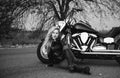 Black and white photo of beautiful biker women posing with motorcycle.