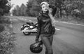 Black and white photo of beautiful biker women posing with motorcycle.