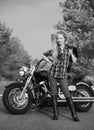 Black and white photo of beautiful biker women posing with motorcycle.