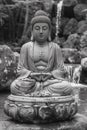 A black and white photo of a buddha statue sitting on top of rocks, AI