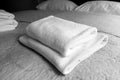 Black and white photo. Clean white towels on the bed in the hotel.