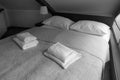 Black and white photo. Clean towels on the bed in the room.