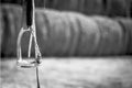 black and white photo, close up horse stirrup in the background haystacks