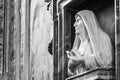 Black and white photo of in close-up of marble sculpture of a nun carved into a niche in the wall inside a catholic church in Rome