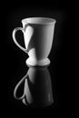 Black and white photo, white coffee cup isolated on black background.