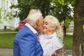 Black and white photo. Elderly man kisses an elderly lady. Concept: family, love, date. Fancy clothes, bright makeup.