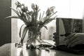 Black and white photo: a faded bouquet in a vase, hands flipping through an old photo album.