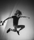 Black and white photo of a frantic and expressive jump, hair scatter in different directions. Portrait of a jumping man on a dark