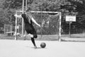 Black and white photo.The girl shoots penalty the towards an empty goal.