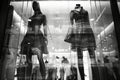 Black and white photo of glass storefronts with manikins, manikins in sold clothes