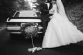 black and white photo of happy young newlywed couple near decorated retro car with plate just married and many jars Royalty Free Stock Photo