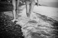 A black and white photo of the legs of a couple in love, in shorts and swimming trunks, walking along the ocean Royalty Free Stock Photo