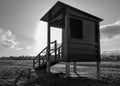 black and white photo of lifeguard house on the sand at a peaceful beach without guard or people at the sunset hour. The sun is Royalty Free Stock Photo