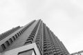 Black and white photo Low angle view of a symmetrical brick tall building corner with cloudy sky at background Royalty Free Stock Photo