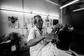 A black and white photo of a male barber giving a haircut in a shop in Phuket, Thailand