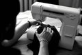 Black and white photo of Man sews clothes on sewing machine