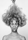 Black and white photo. Woman with colored face painted and tousled hairstyle. Art beauty image.