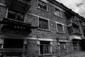 Black and white photo of old abandoned partially collapsed building with intricate stonework, ruined balconies, crashed