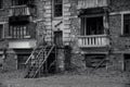 Black and white photo of old abandoned partially collapsed building with intricate stonework, ruined balconies, crashed