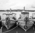 black and white photo of old aged fishing boats lined up in a fishing sea harbor