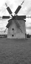 Black and white photo with an old windmill sitting in a field with a cloudy sky Royalty Free Stock Photo