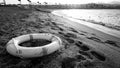 Black and white image of plastic life saving ring lying on the sea beach. Concept of safety during summer holiday Royalty Free Stock Photo