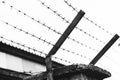 A black and white photo of a scary concrete fence with barbed wire strung over it