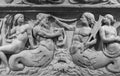 Black and white photo of sculptures carved on an ancient wall showing naked women and male sirens in the sea