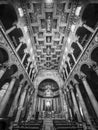 Black and white photo showing perspective of altar hall and decorated ceiling inside roman catholic church