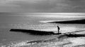 A six year old unrecognisable boy walking along a jetty in the sea, black and white photograph Royalty Free Stock Photo