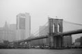 Black and white photo of skyscrapers of Manhattan and Brooklyn bridge on foggy and cloudy day. Famous bridge. Postcard view of New Royalty Free Stock Photo