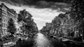 Black and White Photo of Small boats, cars and bikes lining the Herengracht, or Gentlemen`s Canal, in the center of Amsterdam