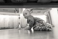 Black and white image of smiling toddler boy sitting on wooden floor at bedroom and looking under the bed Royalty Free Stock Photo