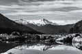 Black and white photo. Stunning landscpae of the reflection of the snow mountain on the river. Blue sky and some cloudy. I