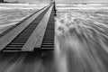 Black and white photo - surf in the storm after sunset, pier, long exposure