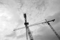 Black and white photo. Tower cranes against the sky.