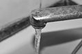 Black and white photo. Water runs from the rusty tap. Old faucet in the bathroom. The texture of the water. Royalty Free Stock Photo