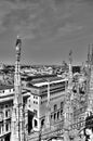 Black and white photo of the white marble statues of Cathedral Duomo di Milano on piazza and the Milan cityscape Royalty Free Stock Photo