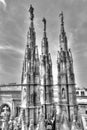 Black and white photo of the white marble statues of Cathedral Duomo di Milano on piazza, Milan cityscape Royalty Free Stock Photo