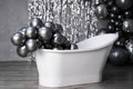 Black and white photo white stylish bathtub in empty room with balloons and confetti