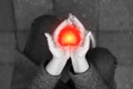 Black and white photo of woman holding on palms red heart staying on the knees. Declaration of love or Charity concept.